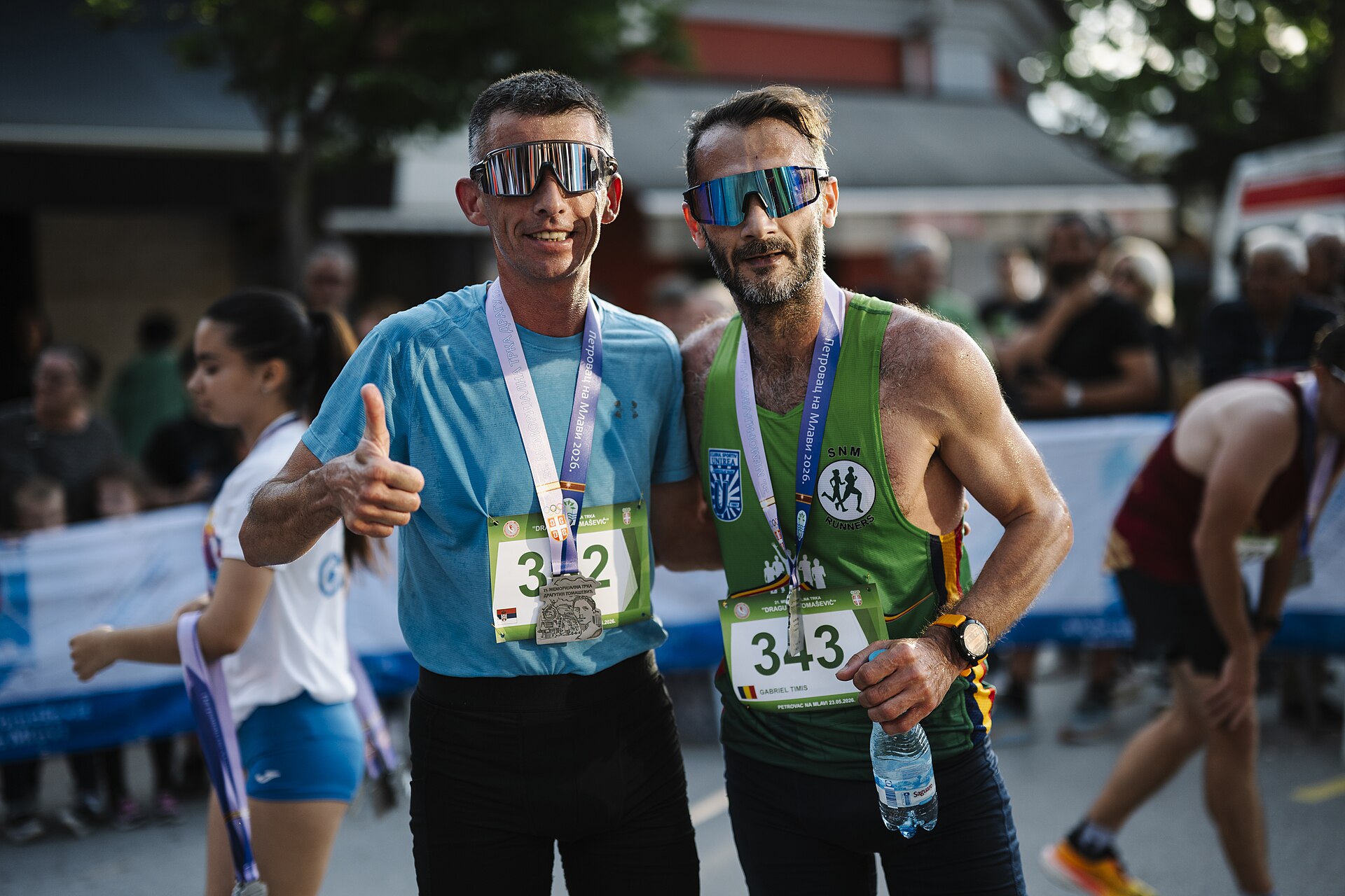 Dois corredores com medalha depois da chegada.